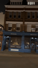 Car passes London shopfront including bookstore, maker space