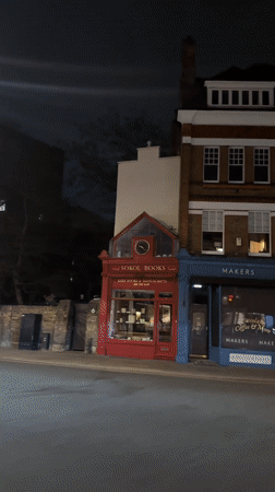 Car passes London shopfront including bookstore, maker space