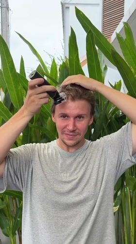 Man cuts own hair outdoors in Chang Phueak, Thailand