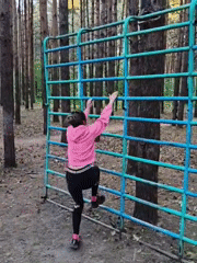 Woman exercises at outdoor playground equipment in Chaikovsky forest