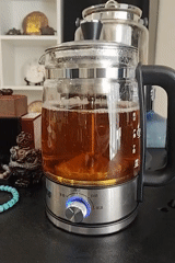 Electric kettle brews dark liquid on counter