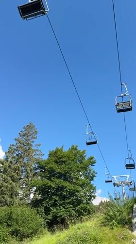 Empty chairlift hangs above green Alpine terrain in Molveno