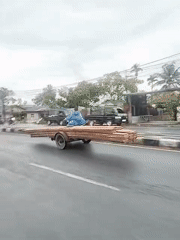 Person rides lumber trailer in rain, Lhokseumawe Indonesia