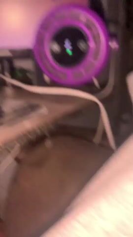 The video shows a close-up of a computer desk setup. On the desk are two computer monitors, a keyboard with RGB lighting, a mouse, and a speaker. The monitor on the right displays a colorful abstract wallpaper with a circular, purple device in front of it. The monitor on the left shows a screen with what appears to be a program or website open, also displaying various colors. The keyboard is illuminated with a rainbow of colors. The overall environment suggests a gaming or computer-focused workspace.