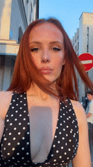Red-haired woman in polka dot dress poses for selfies in Paris
