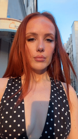 Red-haired woman in polka dot dress poses for selfies in Paris