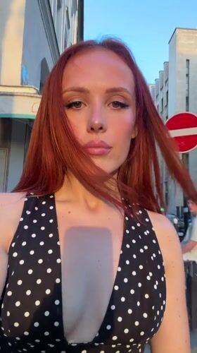 Red-haired woman in polka dot dress poses for selfies in Paris