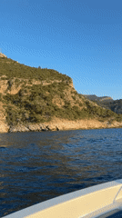 Boat travels along rocky Turkish coastline under clear skies