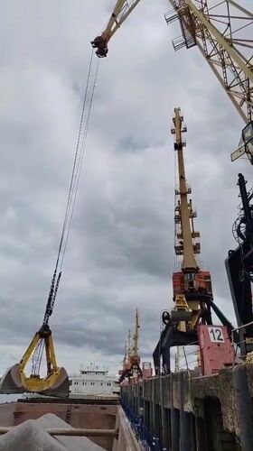 Cargo cranes operate at Rybinsk harbor under cloudy skies