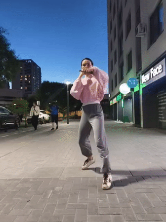 Woman performs street dance on Tyumen sidewalk at dusk