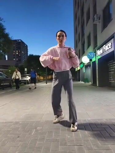 Woman performs street dance on Tyumen sidewalk at dusk