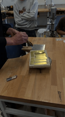 Metalworker heats brass pieces with torch in Jerusalem workshop