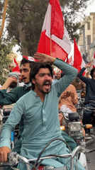 Motorcycle procession with red and white flags rolls through town