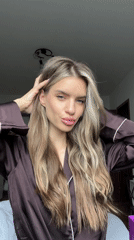 Woman in brown robe poses playfully for camera in Berlin