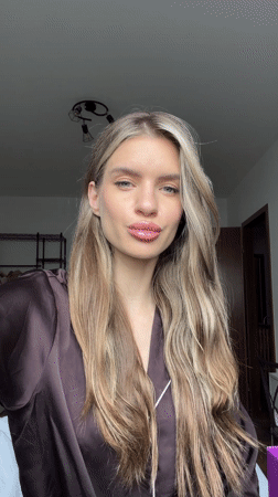 Woman in brown robe poses playfully for camera in Berlin