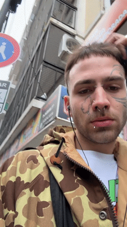 Pierced young man walks Buenos Aires street scene