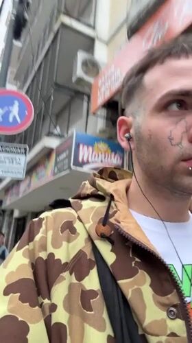 Pierced young man walks Buenos Aires street scene