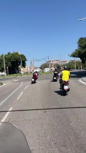 Scooters rolling through sunny Barcelona streets, mid-morning.