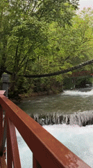 Person crosses wooden bridge over waterfall near Radac, Kosovo