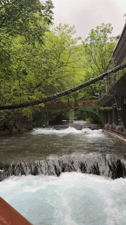 Person crosses wooden bridge over waterfall near Radac, Kosovo