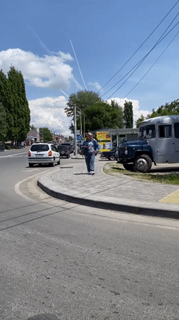 Pedestrian walks sidewalk in Gyumri amid parked vehicles
