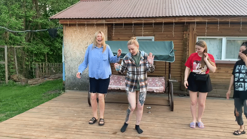 Young women dance at lakeside cabin gathering in Russia