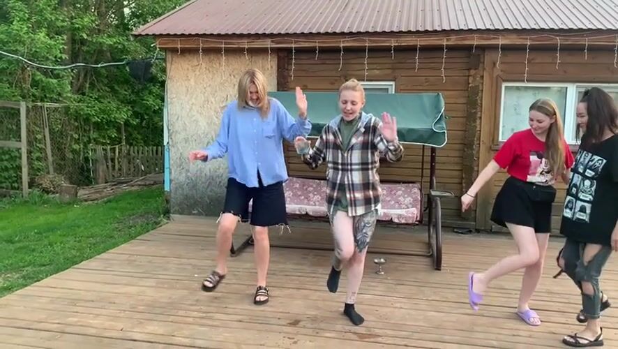 Young women dance at lakeside cabin gathering in Russia