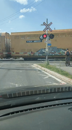 Freight train clears a crossing as a cyclist waits nearby