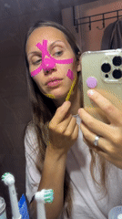 Woman applies kinesiology tape to face in Fethiye bathroom
