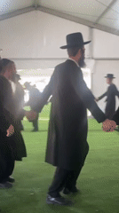 Men dance in circle inside tent in Kiryat Ono