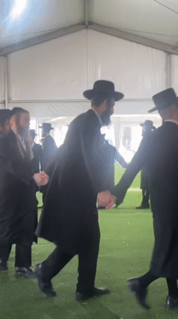 Men dance in circle inside tent in Kiryat Ono