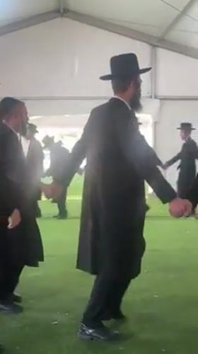 Men dance in circle inside tent in Kiryat Ono