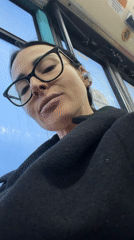 Woman in black observes city through transit window