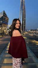Woman in floral dress waves against city skyline