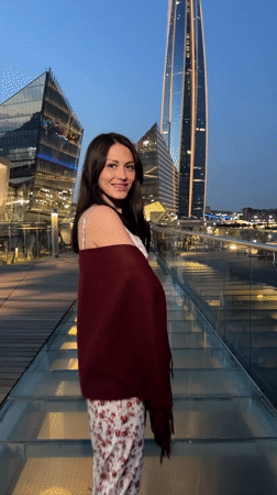 Woman in floral dress waves against city skyline
