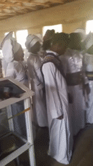 White-robed group gathers in wooden room in Lokoja
