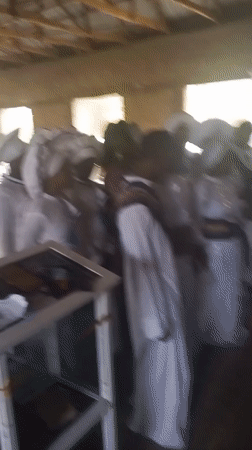 White-robed group gathers in wooden room in Lokoja