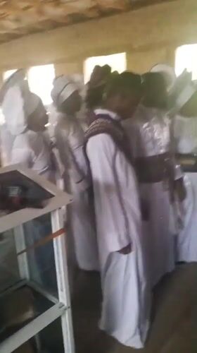 White-robed group gathers in wooden room in Lokoja