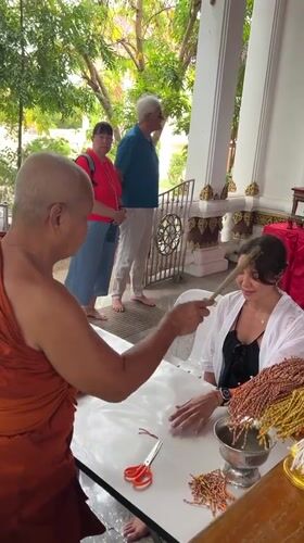 Woman receives traditional Buddhist blessings at Thai temples
