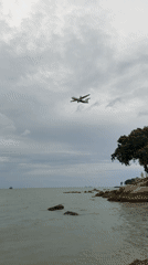 Turboprop on final approach over Ko Samui's rocky shoreline
