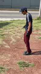 Man with stick plays with object in Mexican residential area
