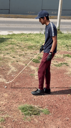 Man with stick plays with object in Mexican residential area