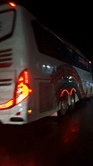 Illuminated rainbow-design bus parked on wet Lhokseumawe street