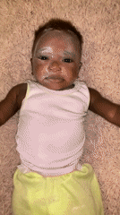 Baby cries on carpet in Nigerian home