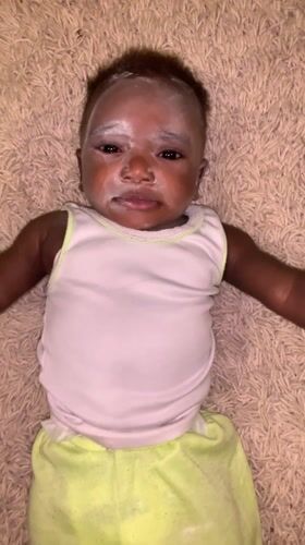 Baby cries on carpet in Nigerian home