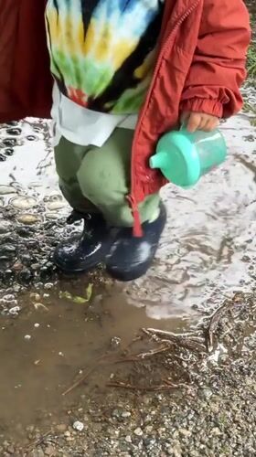 Toddler plays in puddle outside gate in Erba