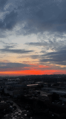 Dawn cityscape features dramatic red-orange horizon lighting