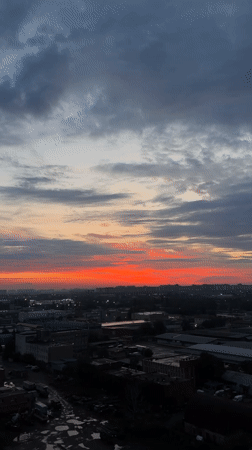 Dawn cityscape features dramatic red-orange horizon lighting
