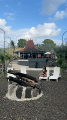 Woman meditates at Balinese pavilion near flowing river in Sidemen