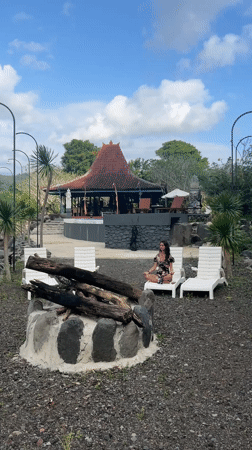 Woman meditates at Balinese pavilion near flowing river in Sidemen